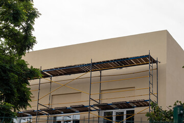 A building with insulated and painted walls with installed scaffolding.
