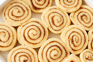 Obraz na płótnie Canvas Background of Raw cinnamon rolls prepared for roasting. Close-up