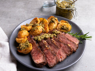 Sliced juicy grilled steak medium rare beef on plate roasted potatoes sauce 