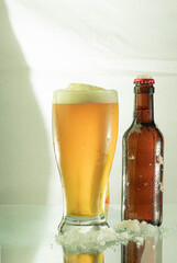 Cool beer on the glass table next to the ice that keeps it cold