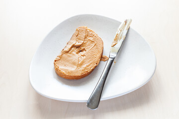 above view of toast with creamy peanut butter and knife on plate on table