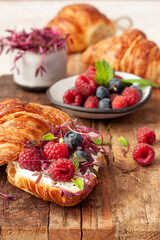 Delicious breakfast with fresh croissants and ripe berries  on wooden background.
