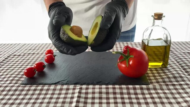 Cook splitting an avocado in half on a table. Concept of gastronomy.