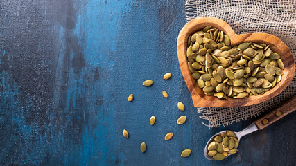 Raw pumpkin seeds in a wooden bowl. Top view, text space