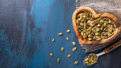 Raw pumpkin seeds in a wooden bowl. Top view, text space