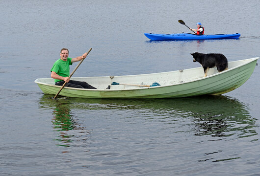 Family on lake. Man with dog on boat and young man on kayak. Finnish Lapland