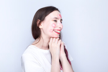 Happy young girl with kisses imprints on her face with red lipstick. World Kissing Day Concept