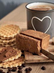 Norwegian brunost cheese with Viennese waffles and a cup of coffee in the background. Breakfast with Traditional Scandinavian brown cheese