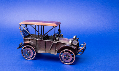 Homemade metal model - toy of an old retro car on a blue background