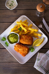 Fish and chips, mushy peas and sauce on white plate. Overhead vertical image