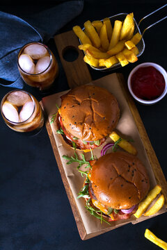Homemade beef burgers and french fries on dark background. Overhead vertical image