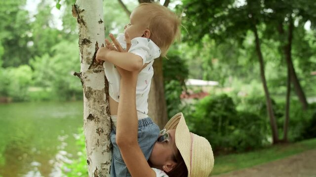 Sister holding small brother on hands outdoors. Family spending time in park