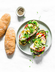 Sandwiches  with grilled eggplant, tomatoes, ham, mozzarella cheese on a light background, top view. Delicious appetizers, tapas