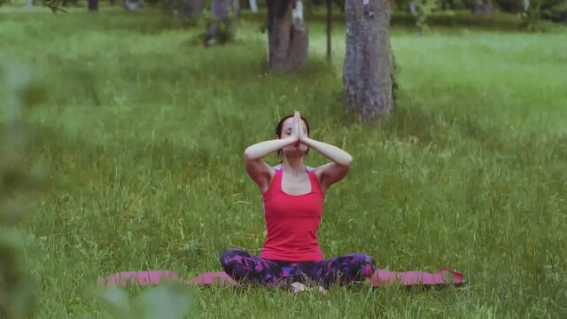 Yoga girl practicing breathing technique exercise with hands raised outdoors in park or garden. Maintaining flexibility and stability in the hip joints is crucial for lower-back health. Prores 422. 