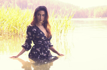 beautiful, young woman poses in the water of a lake