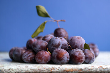 Plum. Fresh plum. Harvest. Autumn harvest. Autumn. Blue plums. Fresh plums on a wooden surface. Fresh plums on wooden table background.