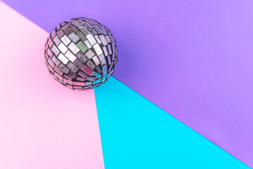 esfera con espejos reflejantes en una esquina sobre superficie tricolor morado rosa azul