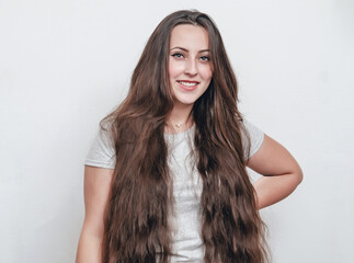 Portrait of a girl with long dark hair on a white background looking at the camera. Pretty smile on...