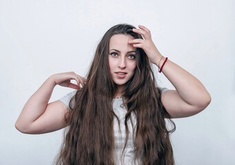 Portrait of a girl with long dark hair on a white background looking at the camera. Light surprise.