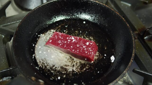 Raw Tuna Steaks served on metal frying pan with lime, chili oil, salt, coriander leaves and lemongrass