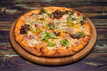 Pizza with meat, cheese, pepper and herbs on a wooden background. Italian national cuisine, delicious pastries in the restaurant.