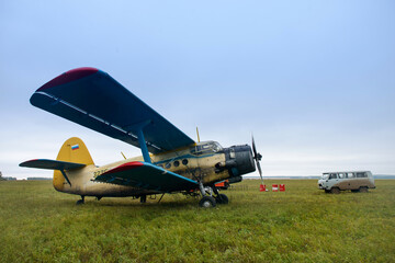 Old russian biplane aircraft An-2 on a green field. Soviet aircraft biplane Antonov AN-2 parked on...