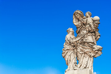 Fototapeta premium Statue of Saint Anne Matej Vaclav Jackel on the north side of Charles Bridge over the river Vltava; statue of a woman with two children in Prague, Czech Republic
