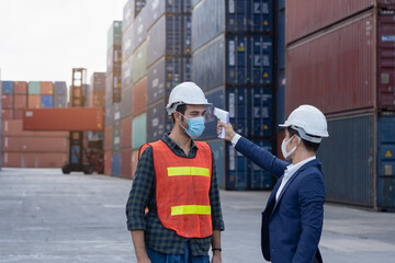 New normal concept,Engineer check the staff integrity by measuring the temperature,wear mask and helmet before working in factory or warehouse area Prevent accident from work or dust and Coronavirus
