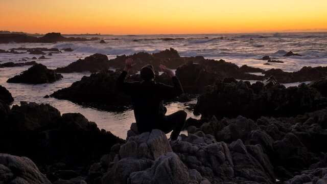 Young men warrior monk practicing silhouette tai chi karate kung Fu on the rocky stones horizon at sunset or sunrise. Art of self-defense. Silhouette on a background of dramatic epic waves