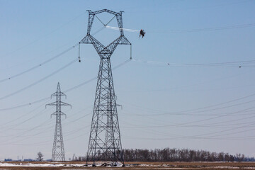 Powered cart carrying linemen on high voltage transmission line.