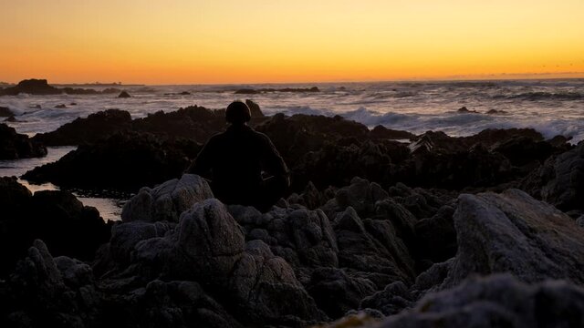 Young men warrior monk practicing silhouette tai chi karate kung Fu on the rocky stones horizon at sunset or sunrise. Art of self-defense. Silhouette on a background of dramatic epic waves