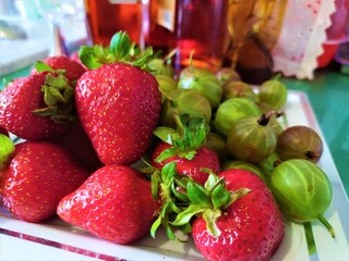 Ripe red strawberries and green gooseberries on the table with cactus