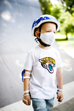 A boy with a skate in a mask, learning to skate, in full protection in quarantine.