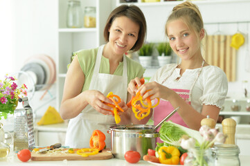 Portrait of cute little girl with mother cooking