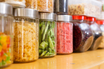 Various dried fruit in transparent jars on shelf in market. Very colorful view with some berries and small pieces of exotic fruits in glass containers. Focus on kiwi.