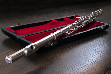 Silver cross flute with red velvet case on wooden background © Stela