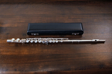 Silver transverse flute with case on wooden background