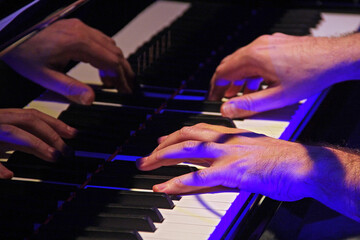 Obraz premium hands with colorful lights playing the piano in show