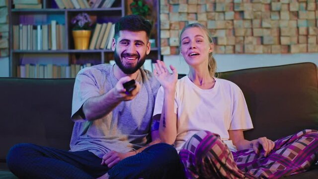 In the evening happy charismatic couple watching tv and smiling large enjoying the time together chatting spending a good time. 4k