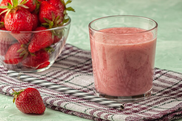 Strawberry smoothie with milk in a glass on a green background, healthy eating for breakfast and snacks