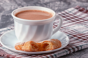 Coffee with cream and freshly baked puffs on a gray background