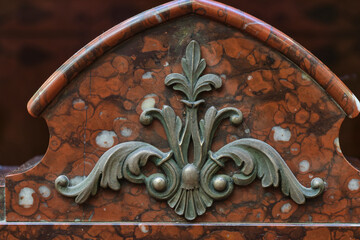 The bas-relief is made of bronze on red marble.