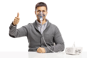 Young man using a nebulizer and showing thumbs up