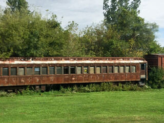 Abandoned rusted railroad car with overgrown weeds