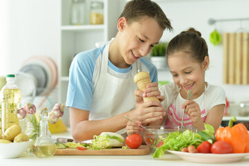 Portrait of cute brother and sister cooking together in kitchen