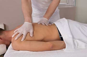 Muscular Man having Chiropractic Back Adjustment . Back pain relief, Injury Rehabilitation. Physiotherapy During the COVID-19 Pandemic, following Safety protocols