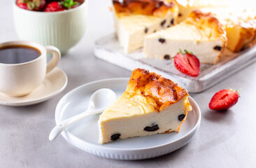 Cottage cheese casserole with raisins and strawberries on gray cement background