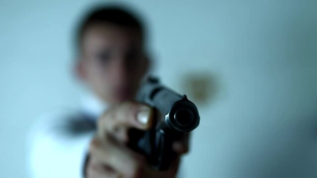 Criminal is holding the gun in his right hand standing at white background. The man with the weapon is threatening someone. The conception of crimes and dangerous criminals.