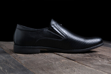 black mens shoes on wooden table on a black background