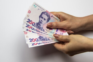 Female hands holds a thousand hryvnia. Ukrainian currency with woman's hands against a white background. One thousand hryvnia with two hundred hryvnia five bills. Ukrainian money. Banknotes of Ukraine